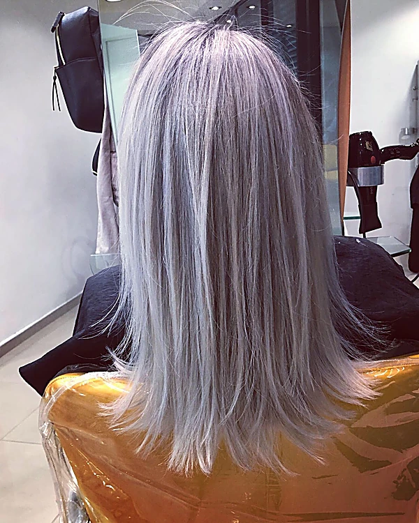 Cabello lacio platino a media espalda, en la silla del salón